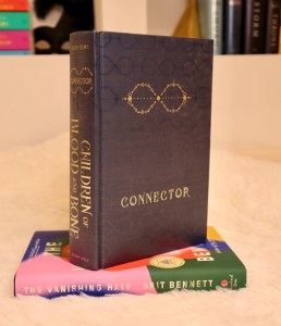 Tomi Adeyemi's book, Children of Blood and Bone, standing on top of The Vanishing Half.